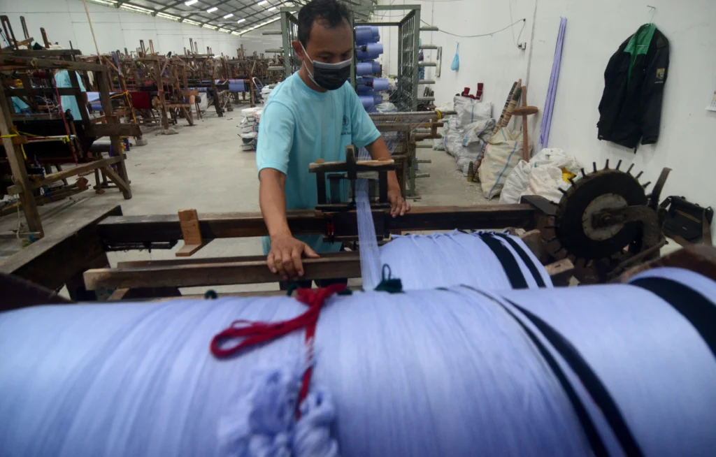 Pekerja menyelesaikan penggulungan benang untuk pembuatan kain sarung menggunakan alat tenun bukan mesin (ATBM) di Industri kain sarung Pohon Korma Desa Pacul, Kabupaten Tegal, Jawa Tengah