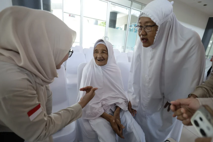 Calon haji tertua Marsiah (kedua kanan) berbincang dengan petugas saat mengikuti upacara pelepasan di Kabupaten Kediri, Jawa Timur