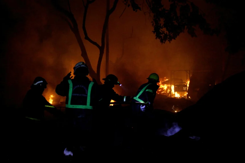 Petugas berusaha memadamkan api yang membakar rumah warga akibat kebakaran Stasiun Pengisian Bulk Elpiji (SPBE)