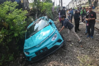Warga mengamati taksi listrik Green SM yang rusak pascakecelakaan dengan KRL Commuter Line dan KA Argo Bromo Anggrek di Bekasi Timur, Bekasi, Jawa Barat, Selasa (28/4/2026). Komite Nasional Keselamatan Transportasi (KNKT) mengerahkan tim investigasi untuk mengumpulkan fakta terkait kecelakaan kereta api di Stasiun Bekasi Timur pada Senin (27/4) malam.