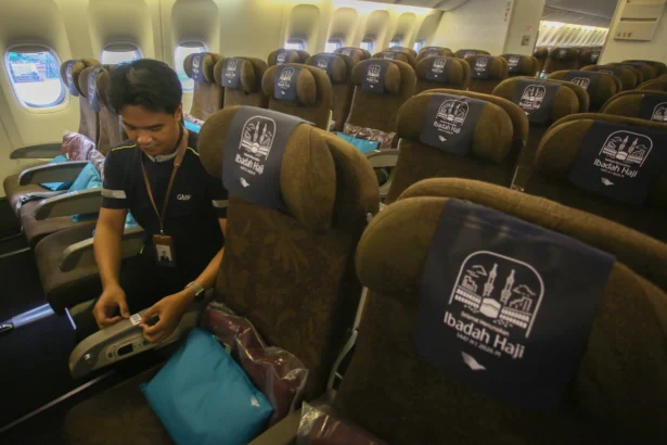 Pekerja memasang nomor urut tempat duduk di pesawat Garuda Indonesia yang akan digunakan untuk armada angkutan haji 1447 H/2026 di hanggar GMF Bandara Soekarno Hatta, Tangerang, Banten