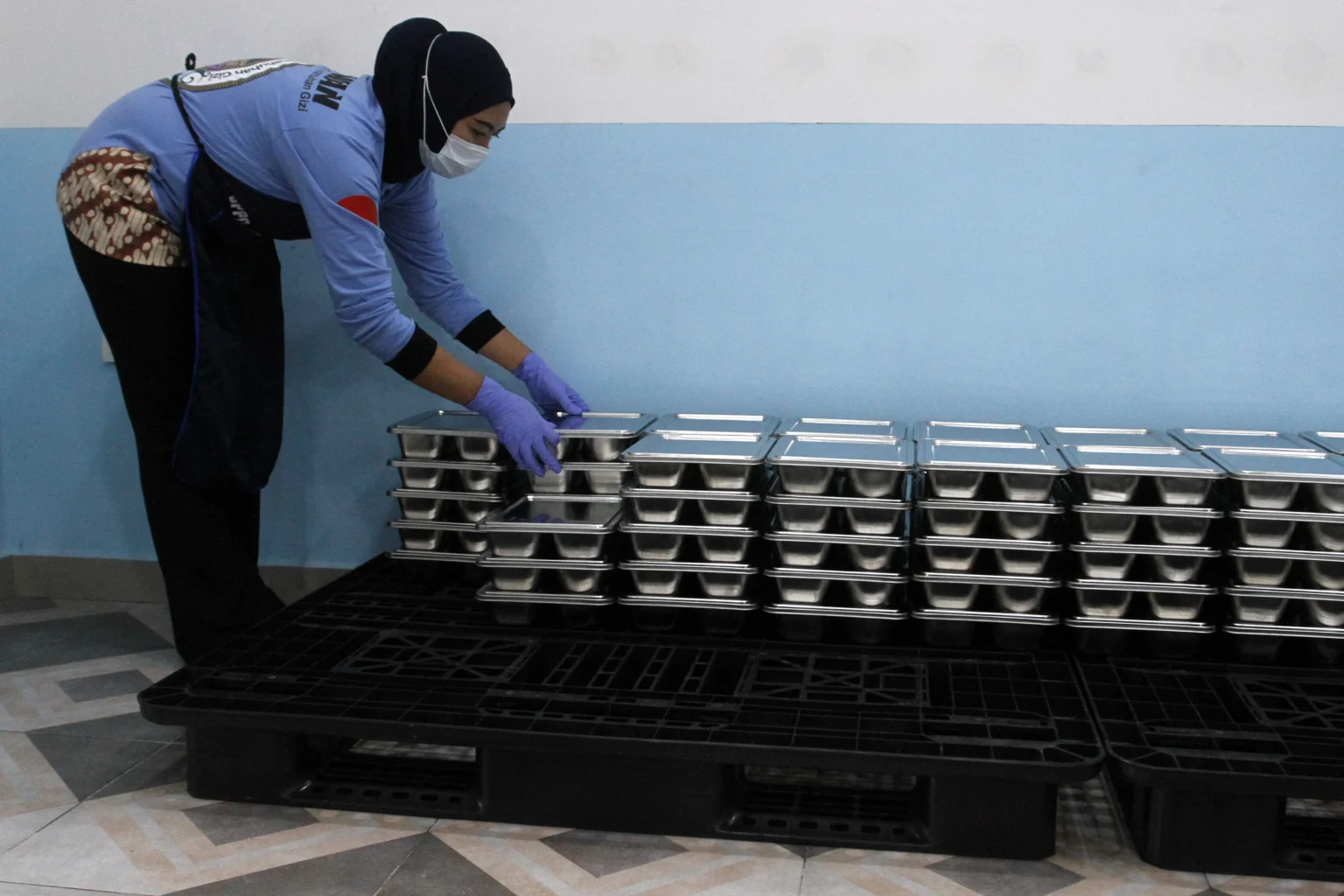 Relawan menata wadah Makan Bergizi Gratis di dapur Satuan Pelayanan Pemenuhan Gizi (SPPG) di Kota Malang, Jawa Timur