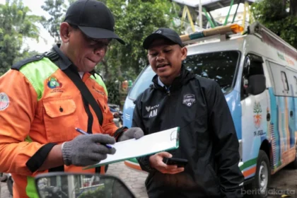Petugas sedang mendata kendaraan yang akan melakukan uji emisi