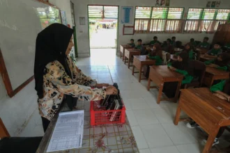 Seorang guru menata gawai milik siswa yang dikumpul sebelum memulai kegiatan belajar mengajar di SMPN 10 Kendari, Kota Kendari, Sulawesi Tenggara, Jumat (10/4/2026). Pihak sekolah setempat menerapkan aturan tentang penggunaan gawai selama jam pembelajaran untuk memberikan lingkungan digital yang aman dalam mendukung penerapan Peraturan Pemerintah (PP) Nomor 17/2025 tentang Pelindungan Anak di Ruang Digital atau PP Tunas dalam lingkungan pendidikan. ANTARA FOTO/Andry Denisah