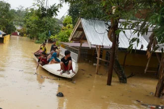 Warga menggunakan perahu saat melintas di depan rumah yang terendam banjir akibat meluapnya Kali Wanggu di Kelurahan Lepo-lepo, Kendari, Sulawesi Tenggara