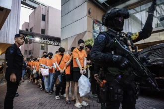 Personel kepolisian menggiring sejumlah tersangka kasus perjudian daring di Perkantoran Hayam Wuruk Plaza Tower, Jakarta, Minggu (10/5/2026). Polri memindahkan 320 orang tersangka Warga Negara Asing (WNA) dan satu orang Warga Negara Indonesia (WNI) yang diamankan dalam pengungkapan kasus perjudian daring jaringan internasional ke sejumlah kantor imigrasi untuk menjalani pemeriksaan lanjutan.