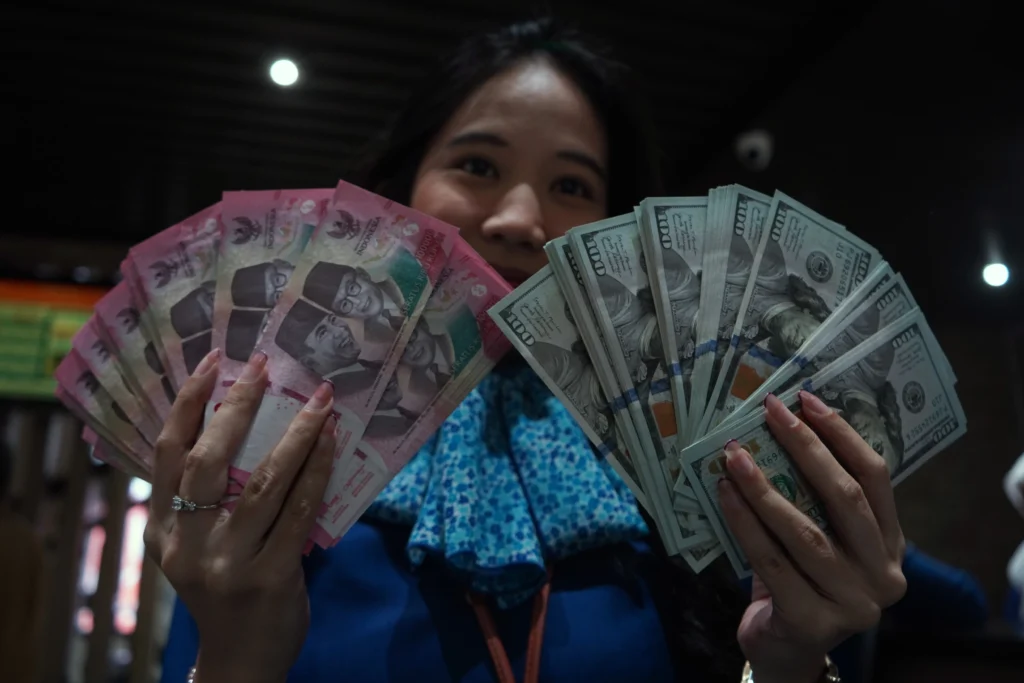 Karyawan menunjukkan uang pecahan rupiah dan dolar Amerika Serikat (AS) di gerai penukaran mata uang asing Haji La Tunrung, Makassar, Sulawesi Selatan, Rabu (20/5/2026). (Sumber: Antara Foto/Hasrul Said/sgd)