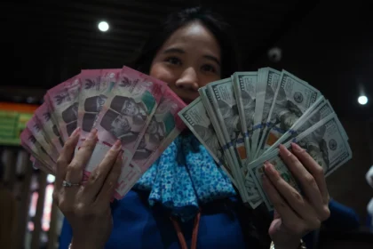 Karyawan menunjukkan uang pecahan rupiah dan dolar Amerika Serikat (AS) di gerai penukaran mata uang asing Haji La Tunrung, Makassar, Sulawesi Selatan, Rabu (20/5/2026). (Sumber: Antara Foto/Hasrul Said/sgd)