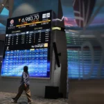 Pekerja berjalan di samping layar pergerakan Indeks Harga Saham Gabungan (IHSG) di Bursa Efek Indonesia (BEI), Jakarta. (Sumber: Antara Foto/Dhemas Reviyanto/sgd)