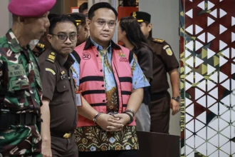 Mantan anggota Ombudsman Yeka Hendra Fatika (kanan) digiring petugas menuju mobil tahanan usai menjalani pemeriksaan di Kejaksaan Agung (Kejagung), Jakarta, Senin (25/5/2026).