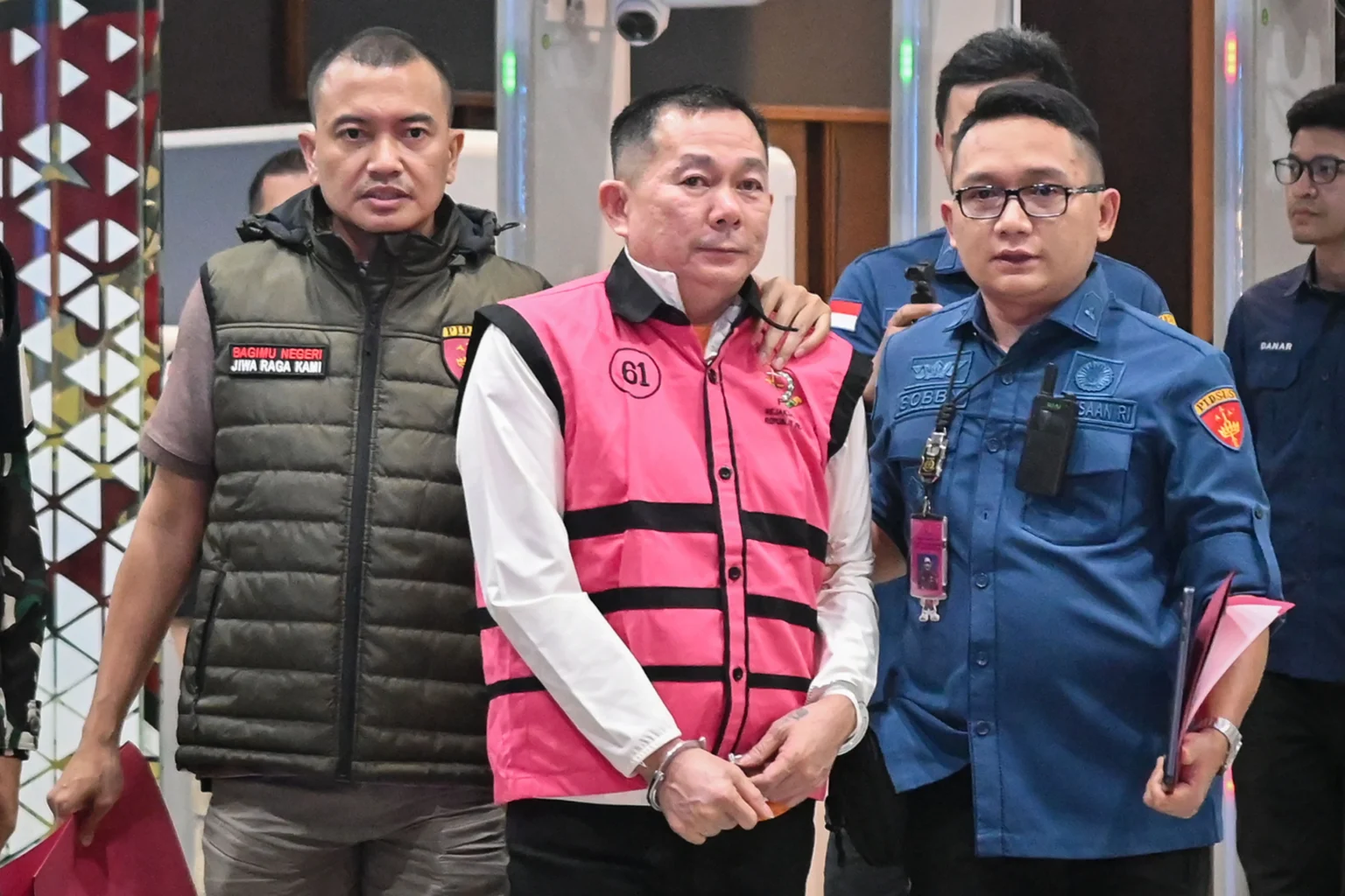 Tersangka kasus dugaan tindak pidana korupsi penyimpangan tata kelola izin usaha pertambangan (IUP) Sudianto (tengah) berjalan menuju mobil tahanan di Kejaksaan Agung, Jakarta, Kamis (21/5/2026).