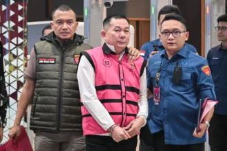 Tersangka kasus dugaan tindak pidana korupsi penyimpangan tata kelola izin usaha pertambangan (IUP) Sudianto (tengah) berjalan menuju mobil tahanan di Kejaksaan Agung, Jakarta, Kamis (21/5/2026).