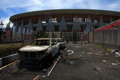 Warga melihat bangkai kendaraan setelah terbakar di Stadion Lukas Enembe, Kabupaten Jayapura, Papua,