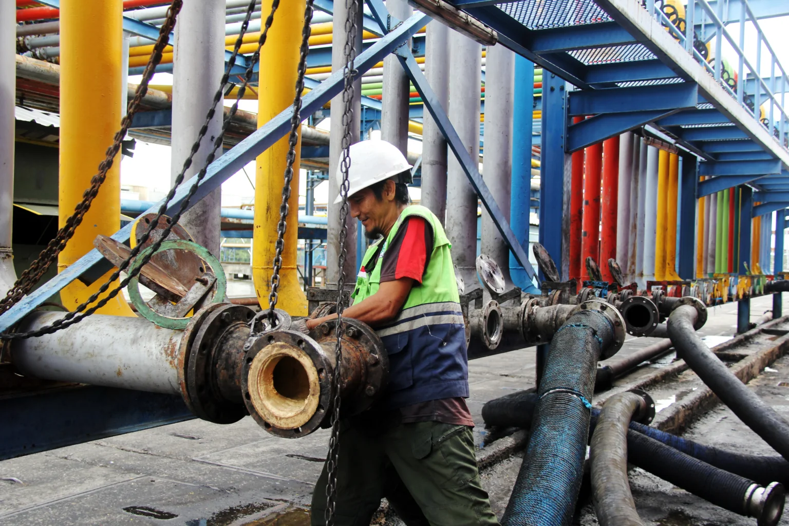 Seorang pekerja memasang sambungan pipa untuk proses pemindahan material crude palm oil (CPO) ke dalam kapal tanker di Dermaga B Curah Cair Pelabuhan PT Pelindo Multi Terminal (SPMT) Branch Dumai, Riau, Rabu (13/5/2026).