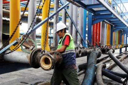 Seorang pekerja memasang sambungan pipa untuk proses pemindahan material crude palm oil (CPO) ke dalam kapal tanker di Dermaga B Curah Cair Pelabuhan PT Pelindo Multi Terminal (SPMT) Branch Dumai, Riau, Rabu (13/5/2026).