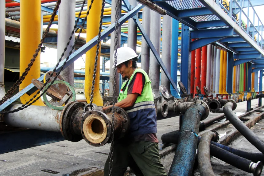 Seorang pekerja memasang sambungan pipa untuk proses pemindahan material crude palm oil (CPO) ke dalam kapal tanker di Dermaga B Curah Cair Pelabuhan PT Pelindo Multi Terminal (SPMT) Branch Dumai, Riau, Rabu (13/5/2026).