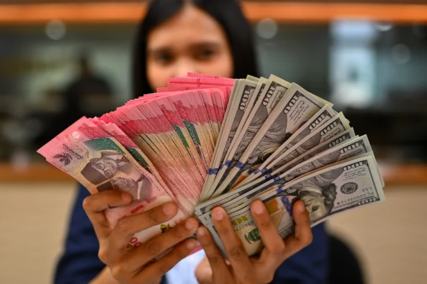 Karyawan memperlihatkan uang pecahan rupiah dan dolar Amerika Serikat (AS) di gerai penukaran mata uang asing Ayu Masagung, Jakarta. (Sumber: Antara Foto/Indrianto Eko Suwarso/kye)
