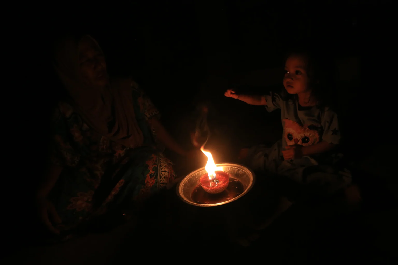 Warga bersama anak menggunakan lampu penerangan tradisional saat terjadi pemadaman listrik di Desa Suak Raya, Johan Pahlawan, Aceh Barat, Aceh, Sabtu (23/5/2026).