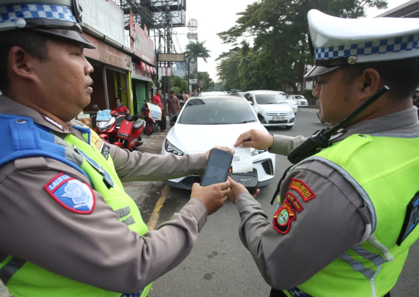Petugas Satlantas Polres Metro Tangerang Kota mencetak bukti tilang elektronik menggunakan perangkat tilang elektronik portabel (ETLE Handheld) terhadap kendaraan yang melanggar larangan parkir di Jalan Daan Mogot, Tangerang, Banten, Kamis (7/5/2026).