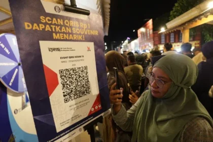 Warga memindai kode QRIS untuk mendapakan suvenir saat edukasi keuangan di pasar malam Kabupaten Kediri, Jawa Timur.