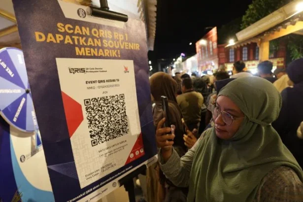 Warga memindai kode QRIS untuk mendapakan suvenir saat edukasi keuangan di pasar malam Kabupaten Kediri, Jawa Timur.