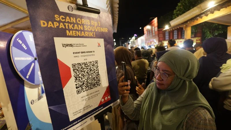 Warga memindai kode QRIS untuk mendapakan suvenir saat edukasi keuangan di pasar malam Kabupaten Kediri, Jawa Timur.