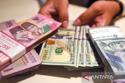 Petugas menunjukan uang pecahan dolar AS dan rupiah di Bank BSI, Jakarta.
