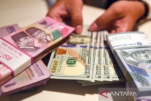 Petugas menunjukan uang pecahan dolar AS dan rupiah di Bank BSI, Jakarta.
