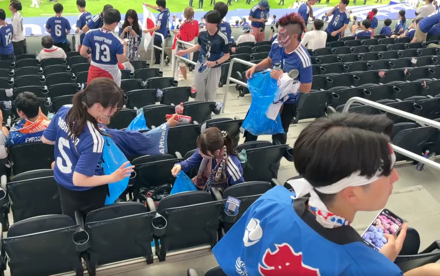 Suporter membersihkan sampah usai pertandingan antara Belanda melawan Jepang.