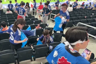 Suporter membersihkan sampah usai pertandingan antara Belanda melawan Jepang.