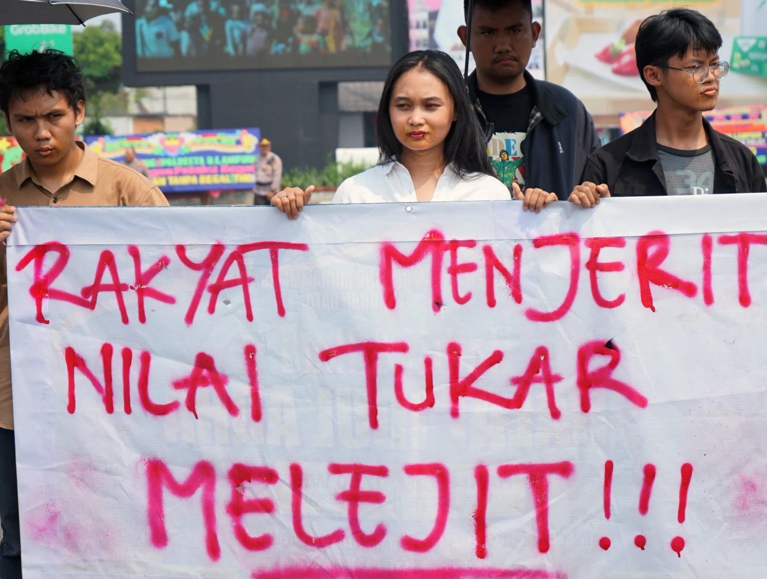 Mahasiswa yang tergabung dalam Liga Mahasiswa Nasional untuk Demokrasi (LMND) dengan mulut terjahit memajang spanduk ketika berunjuk rasa di Tugu Adipura, Bandar Lampung, Lampung, Rabu (10/6/2026).