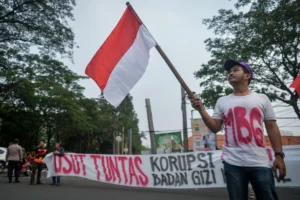 Peserta aksi yang tergabung dalam Lingkar Aspirasi Publik (LAP) mengibarkan bendera Merah Putih saat unjuk rasa di Tugu Adipura, Kota Tangerang, Banten, Rabu (10/6/2026).