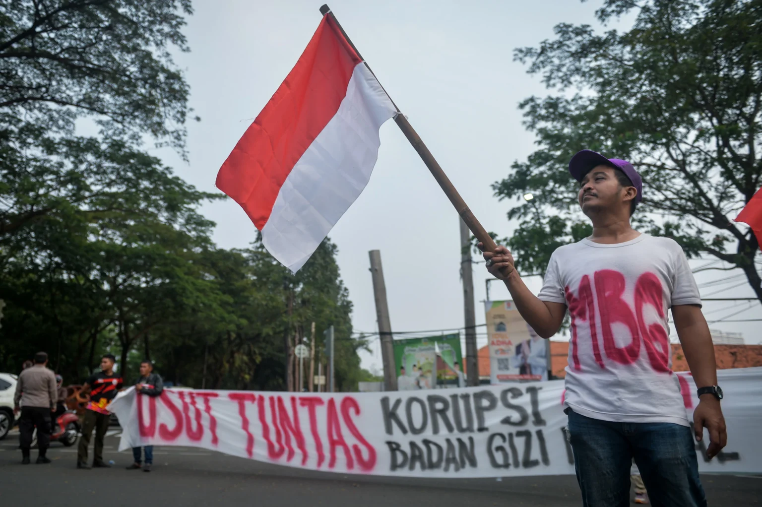 Peserta aksi yang tergabung dalam Lingkar Aspirasi Publik (LAP) mengibarkan bendera Merah Putih saat unjuk rasa di Tugu Adipura, Kota Tangerang, Banten, Rabu (10/6/2026).