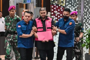 Tersangka kasus dugaan tindak pidana korupsi tata kelola program Makan Bergizi Gratis (MBG) Glory Harimas Sihombing (tengah) berjalan menuju mobil tahanan di Kejaksaan Agung, Jakarta, Kamis (18/6/2026).