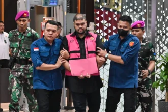 Tersangka kasus dugaan tindak pidana korupsi tata kelola program Makan Bergizi Gratis (MBG) Glory Harimas Sihombing (tengah) berjalan menuju mobil tahanan di Kejaksaan Agung, Jakarta, Kamis (18/6/2026).