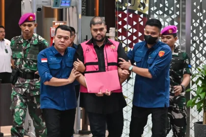 Tersangka kasus dugaan tindak pidana korupsi tata kelola program Makan Bergizi Gratis (MBG) Glory Harimas Sihombing (tengah) berjalan menuju mobil tahanan di Kejaksaan Agung, Jakarta, Kamis (18/6/2026).