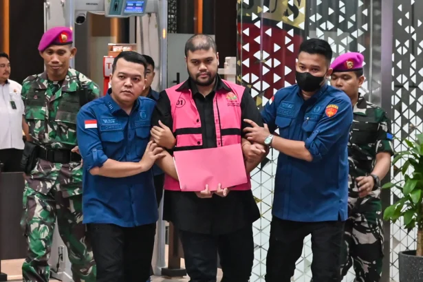 Tersangka kasus dugaan tindak pidana korupsi tata kelola program Makan Bergizi Gratis (MBG) Glory Harimas Sihombing (tengah) berjalan menuju mobil tahanan di Kejaksaan Agung, Jakarta, Kamis (18/6/2026).