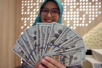 Karyawan memperlihatkan uang dolar Amerika Serikat (AS) di Kantor Cabang Bank Syariah Indonesia, Jakarta, Rabu (3/6/2026).