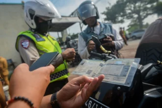 Polisi lalu lintas bersama petugas Sistem Administrasi Manunggal Satu Atap (Samsat) memeriksa STNK pengendara roda dua saat operasi penertiban pajak kendaraan bermotor di Cikupa, Kabupaten Tangerang, Banten, Selasa (19/5/2026).