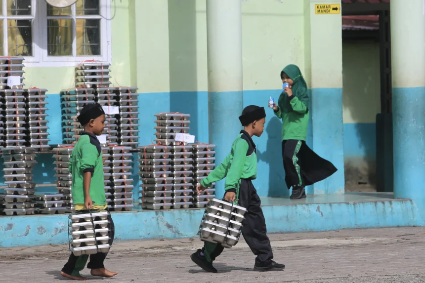 Sejumlah siswa membawa ompreng Makan Bergizi Gratis (MBG) di komplek Madrasah Ibtidayyah Negeri (MIN) 11 Aceh Barat dan Madrasah Tsanawiyah Swasta (MTS) Harapan Bangsa Desa Kuta Padang, Johan Pahlawan, Aceh Barat, Aceh, Rabu (20/5/2026).