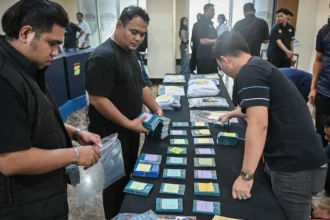 Petugas merapikan barang bukti kasus penipuan perjalanan umrah Hanania Group saat rilis di Polda Metro Jaya, Jakarta, Selasa (2/6/2026).