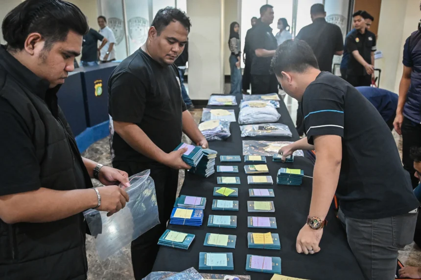 Petugas merapikan barang bukti kasus penipuan perjalanan umrah Hanania Group saat rilis di Polda Metro Jaya, Jakarta, Selasa (2/6/2026).