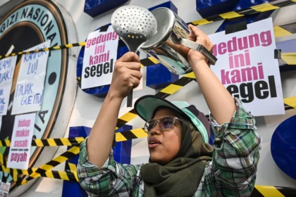 Warga yang tergabung dalam aliansi MBG Watch membawa peralatan dapur saat aksi unjuk rasa di depan kantor Badan Gizi Nasional (BGN), Jakarta Pusat