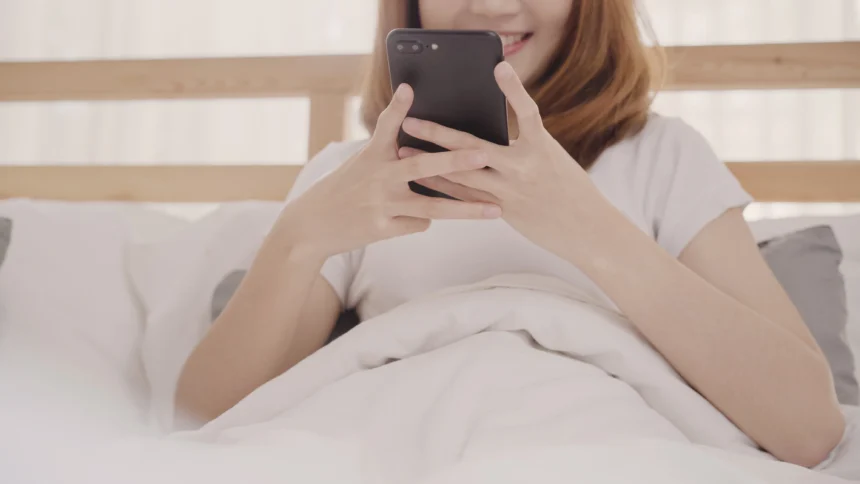 Ilustrasi main handphone di tempat tidur