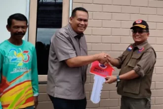Sekretaris Utama BNPB Rustian menyerahkan kunci rumah hunian tetap mandiri kepada warga terdampak bencana Siklon Senyar wilayah Sumatra Barat, 10 Juli 2026.