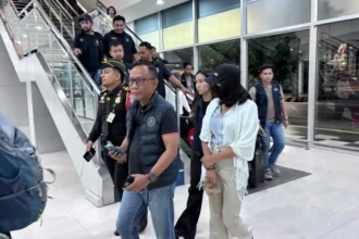 Buron kasus TPPO Leny Agustya, memakai topi dan masker, diamankan penyidik Polri dan petugas Imigrasi.