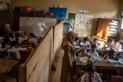 Guru saat mengajar di ruang kelas yang disekat akibat bangunan kelas ambruk di SD Negeri Tanggirejo, Tegowanu, Grobogan, Jawa Tengah.