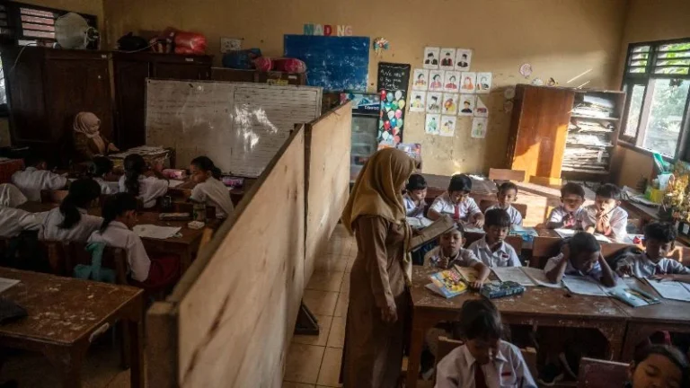 Guru saat mengajar di ruang kelas yang disekat akibat bangunan kelas ambruk di SD Negeri Tanggirejo, Tegowanu, Grobogan, Jawa Tengah.