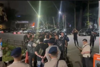 Tangkapan layar yang menampilkan belasan pria berseragam dinas dan membawa senjata laras panjang di kawasan Polda Metro Jaya
