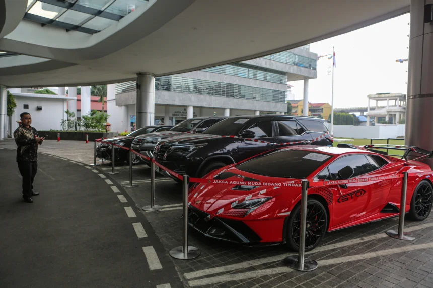 Pekerja mengamati mobil sitaan penyidik Jaksa Agung Muda Bidang Tindak Pidana Khusus (Jampidsus) di Kejaksaan Agung, Jakarta, Jumat (3/7/2026).